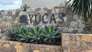 Un muro de piedra con el nombre 'NUCAS' y un letrero metálico decorativo.