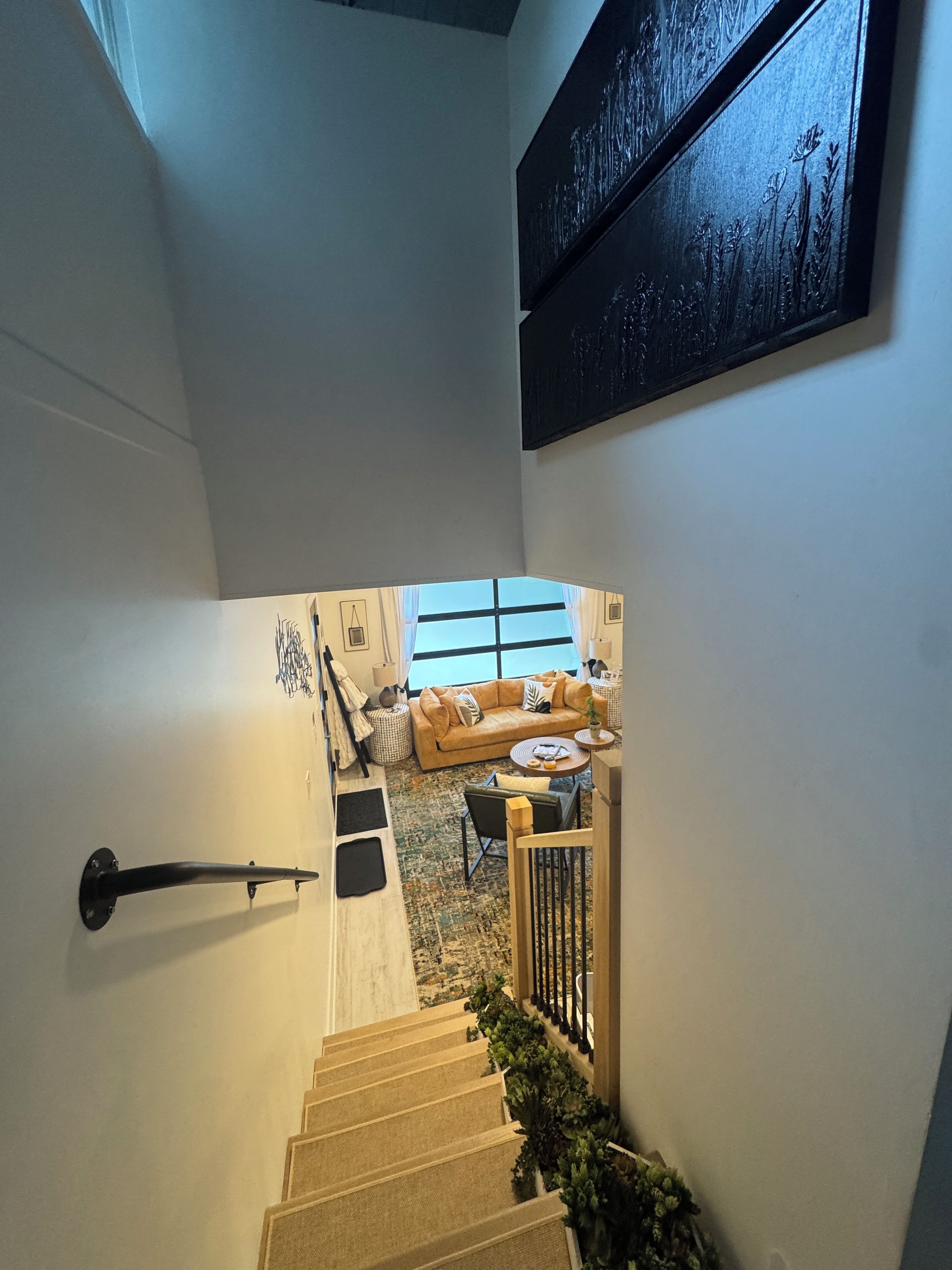 A staircase leading to a living area with a sofa, a coffee table, and a view of the outdoors.