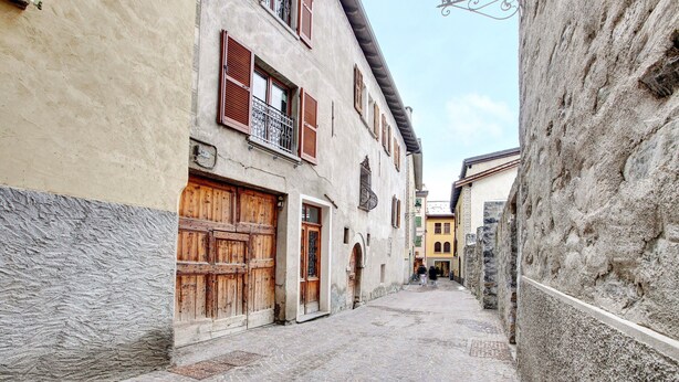 A narrow cobblestone street flanked by historic buildings with wooden doors and balconies. - Studio Apartment 'Premesan 4' with Wi-Fi (Bormio)