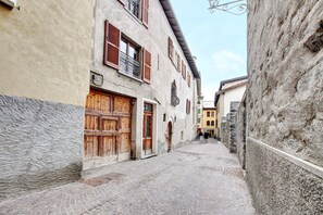A narrow cobblestone street flanked by historic buildings with wooden doors and balconies.