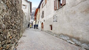 A narrow cobblestone street flanked by historic stone buildings with wooden shutters and a stone wall on one side. - Studio Apartment 'Premesan 4' with Wi-Fi (Bormio)