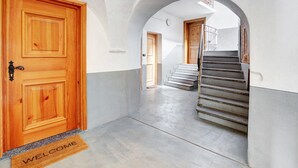 A hallway with a wooden door, a welcome mat, and a staircase. - Studio Apartment 'Premesan 4' with Wi-Fi (Bormio)