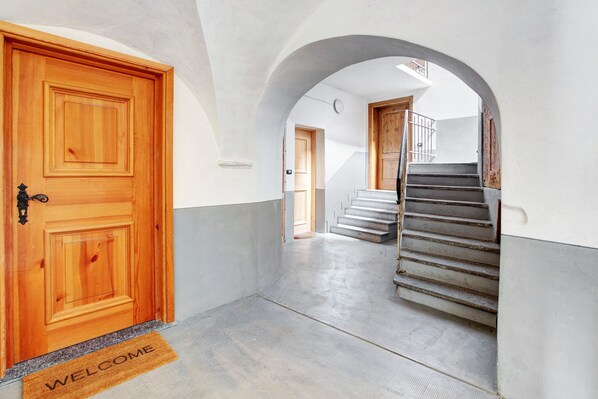 A hallway with a wooden door, a welcome mat, and a staircase.