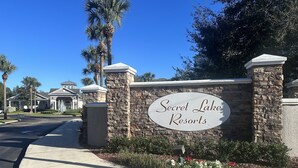 Naamplaatje voor Secret Lake Resorts, met een stenen muur en een heldere lucht.