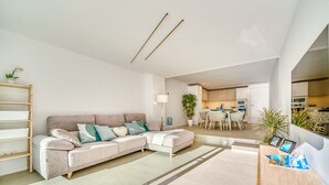 A modern living room with a sectional sofa, a dining area, and a kitchen in the background.