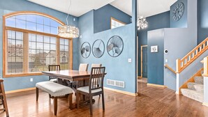 A dining area with a wooden table and chairs, a chandelier, and a large window with blinds. - Wonderful home in prime Rosemount location.

 (Rosemount)