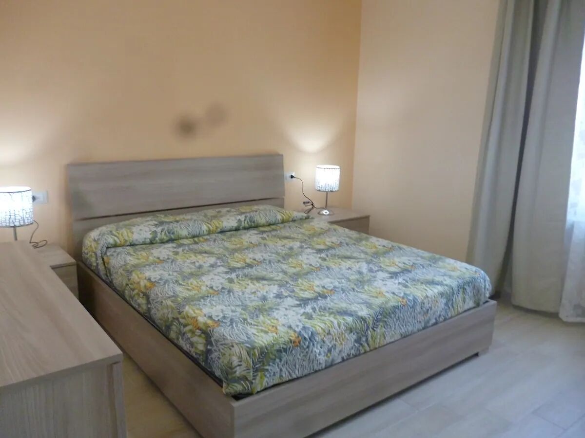 A bedroom with a bed, bedside tables, and a lamp.