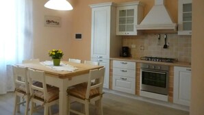 Une cuisine avec des meubles blancs, une cuisinière et une table à manger avec des chaises.