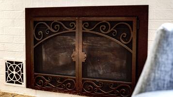 Una celosía metálica decorativa con diseños intrincados sobre una pared de ladrillo blanco.