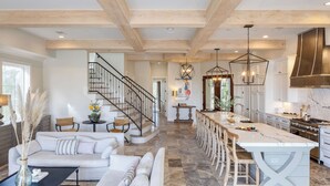 Une cuisine moderne dotée d’un grand îlot central, d’un coin repas avec une longue table et d’un escalier menant à un autre niveau.