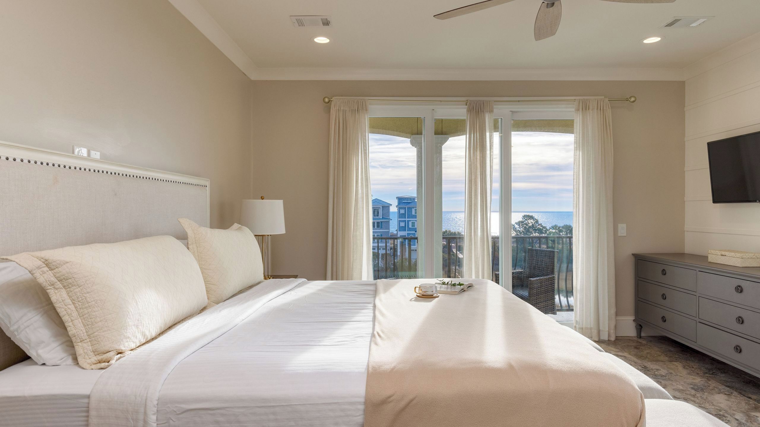 A hotel room with a bed, a bedside lamp, a dresser, and a TV on the wall.