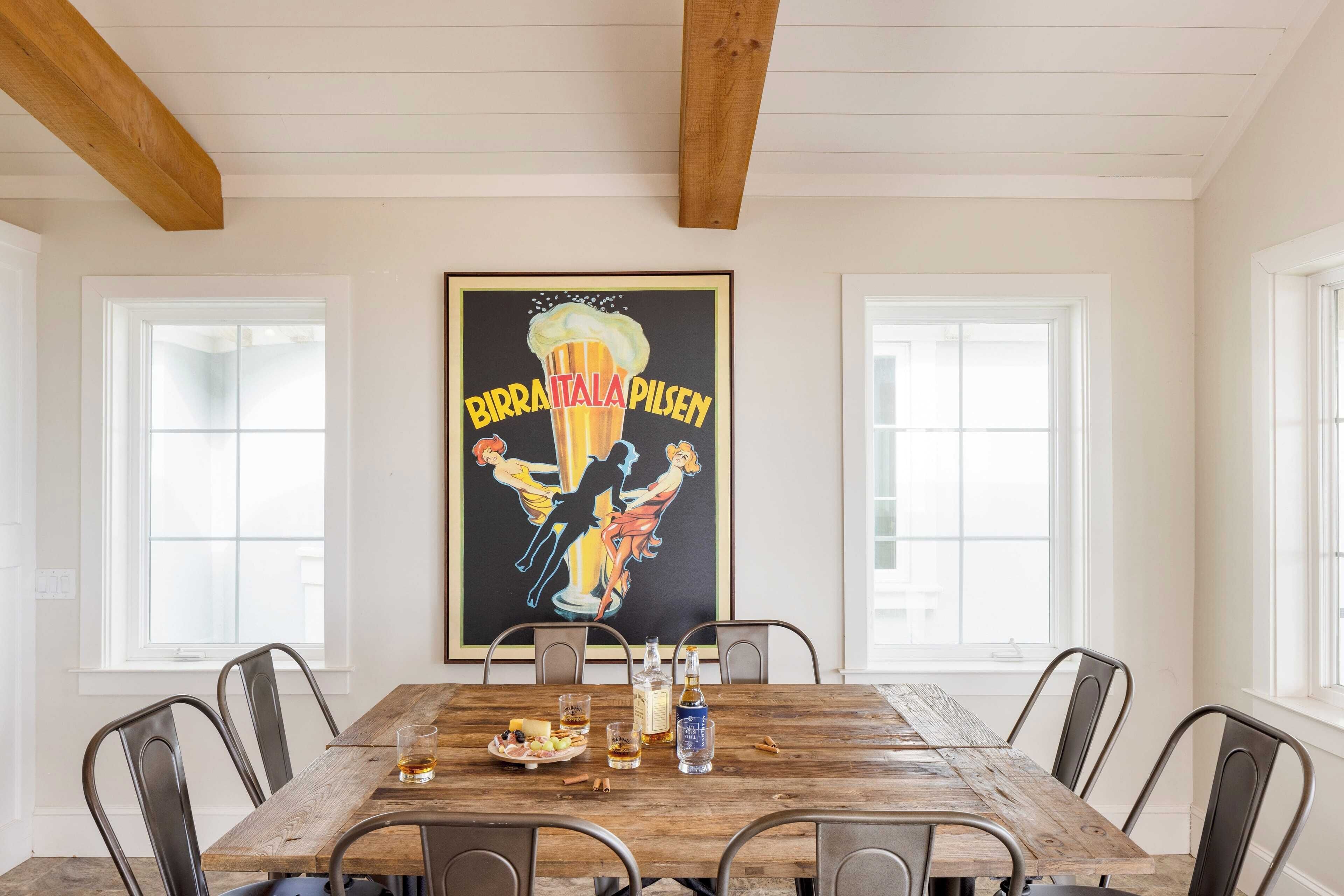 Un comedor con una mesa de madera, sillas de metal y un cartel en la pared.