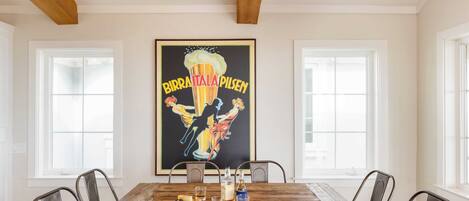 A dining area with a wooden table, metal chairs, and a poster on the wall.