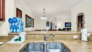 A kitchen with a double sink, granite countertop, and a hanging light fixture. - Awesome Vacation Destination! 1304 Tuscana Resort (Davenport)