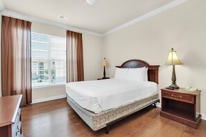 Habitación de hotel con una cama grande, dos mesitas de noche, un escritorio y una ventana con cortinas.