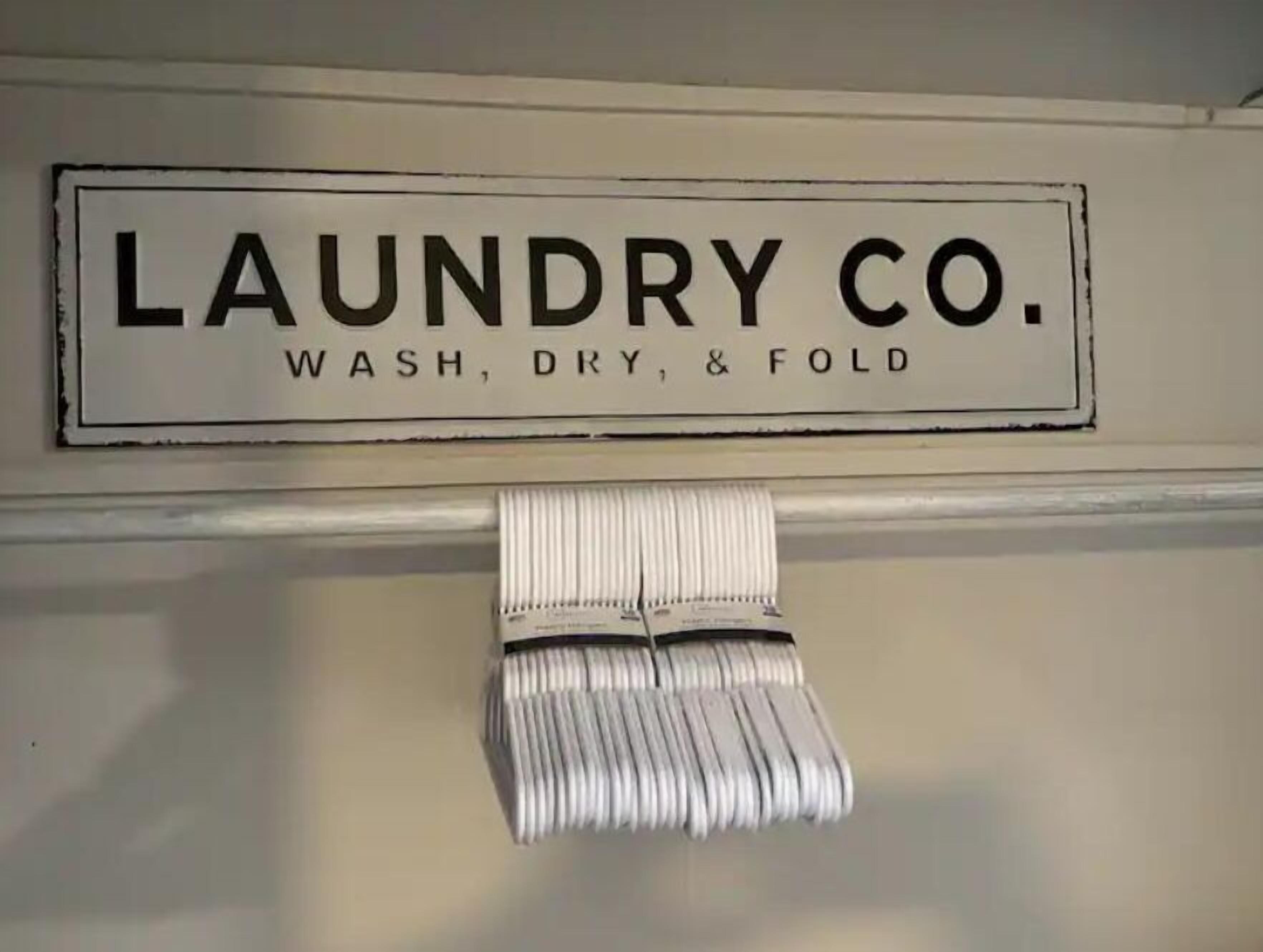 A laundry sign with the text "LAUNDRY CO. WASH, DRY, & FOLD" and a folded white towel hanging below it.
