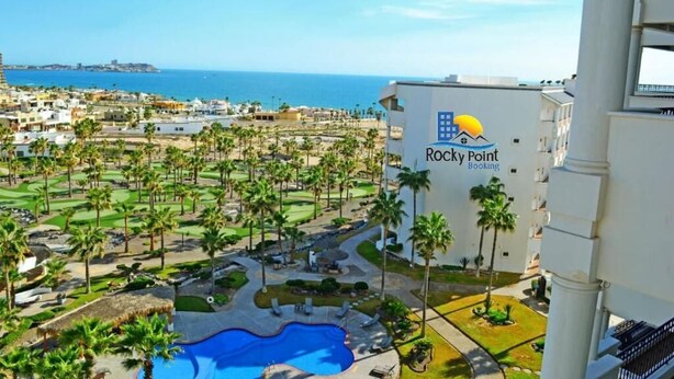 Un resort con piscina, palmeras y vista al océano.