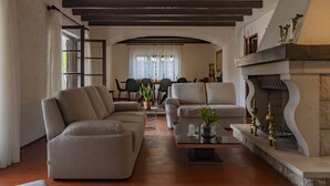 Ein modernes Wohnzimmer mit einem Ecksofa, einem Kamin und einem Essbereich im Hintergrund.