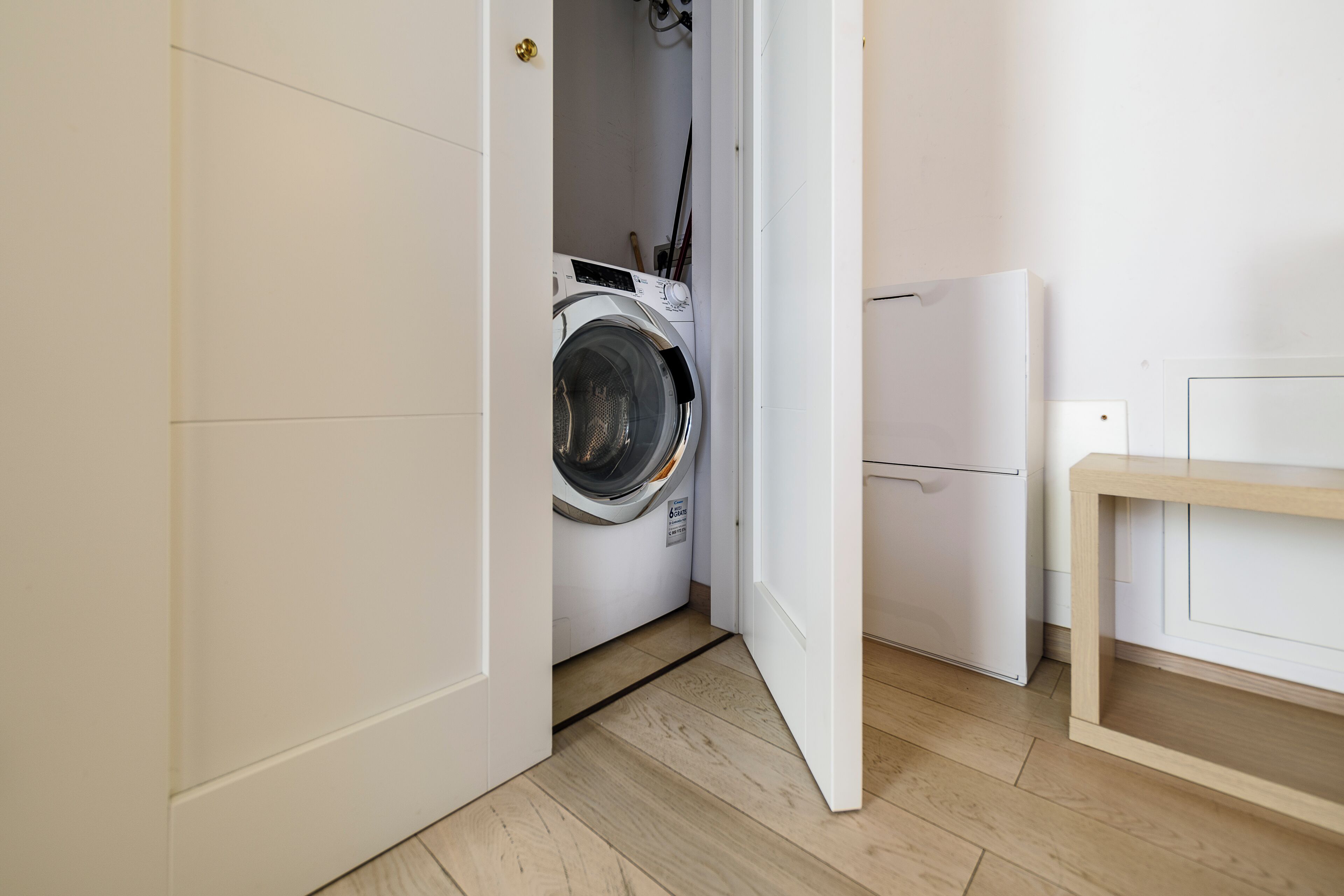 A laundry room with a washing machine, a dryer, and a wooden bench.