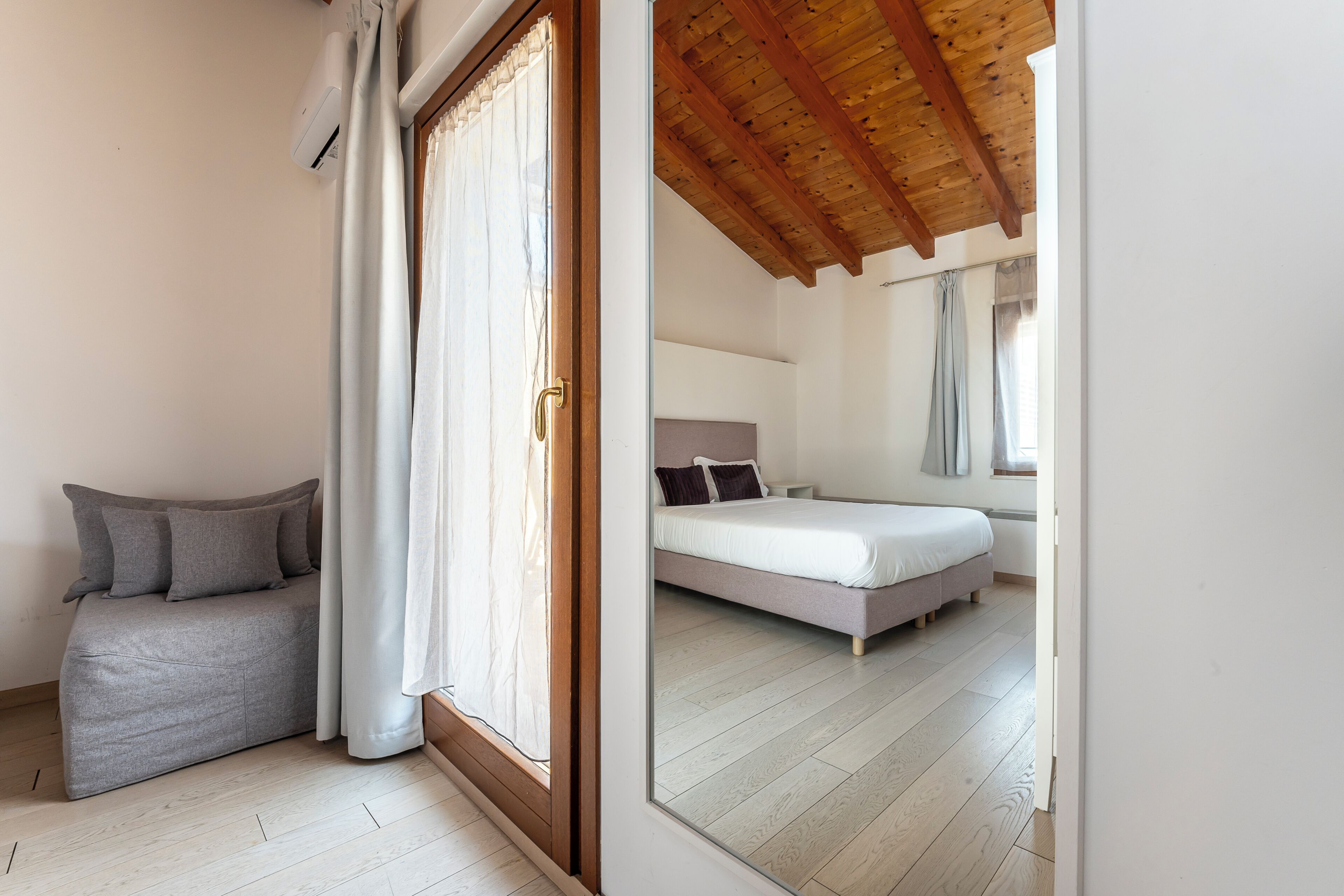 A bedroom with a bed, a sofa, and a wooden ceiling.