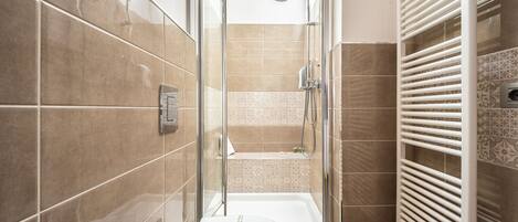 A bathroom with a glass-enclosed shower, a white toilet, and a white radiator.