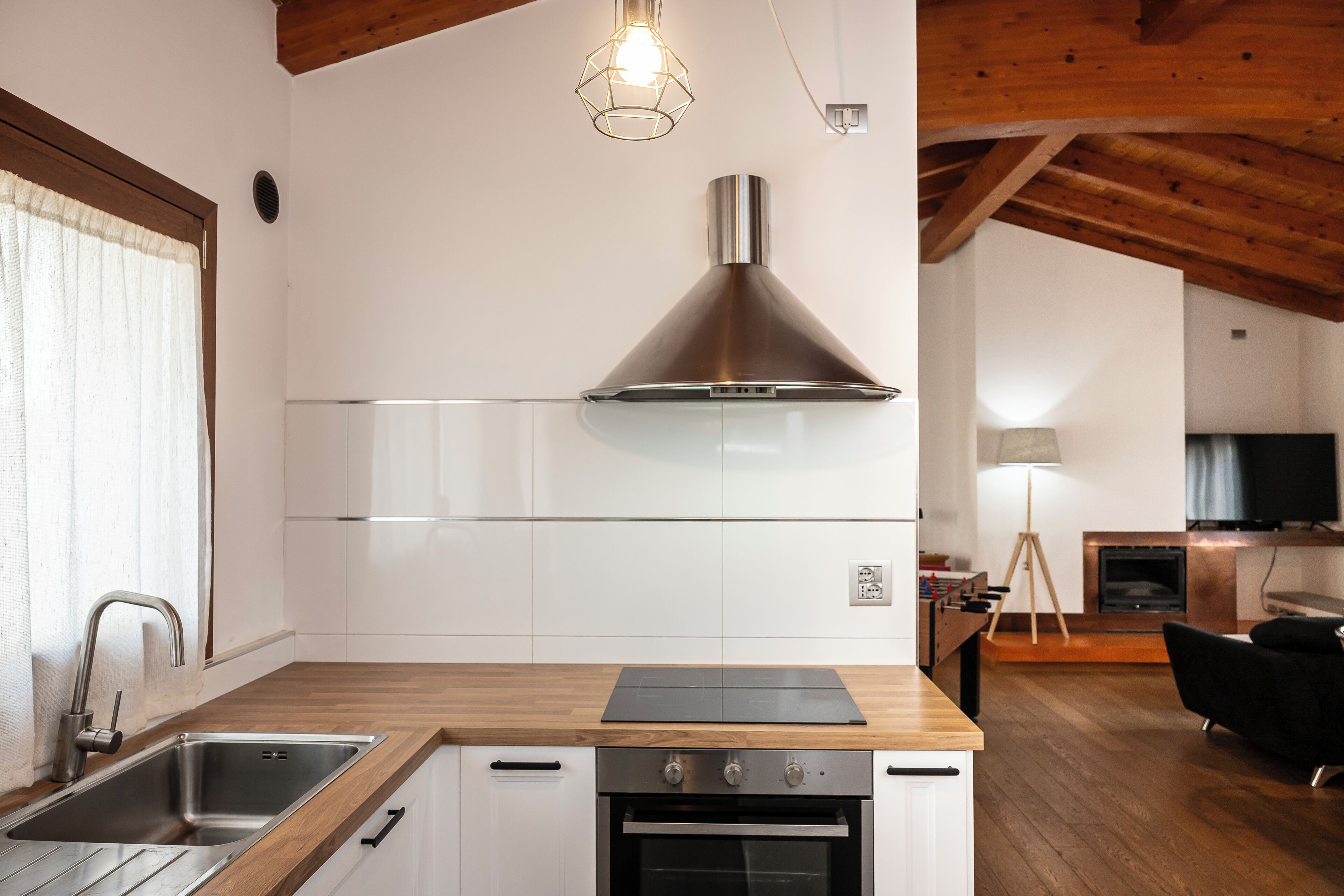 Une cuisine moderne dotée d’une hotte en acier inoxydable, d’un plan de travail en bois et de meubles blancs.