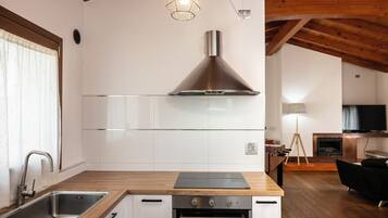 Une cuisine moderne dotée d’une hotte en acier inoxydable, d’un plan de travail en bois et de meubles blancs.
