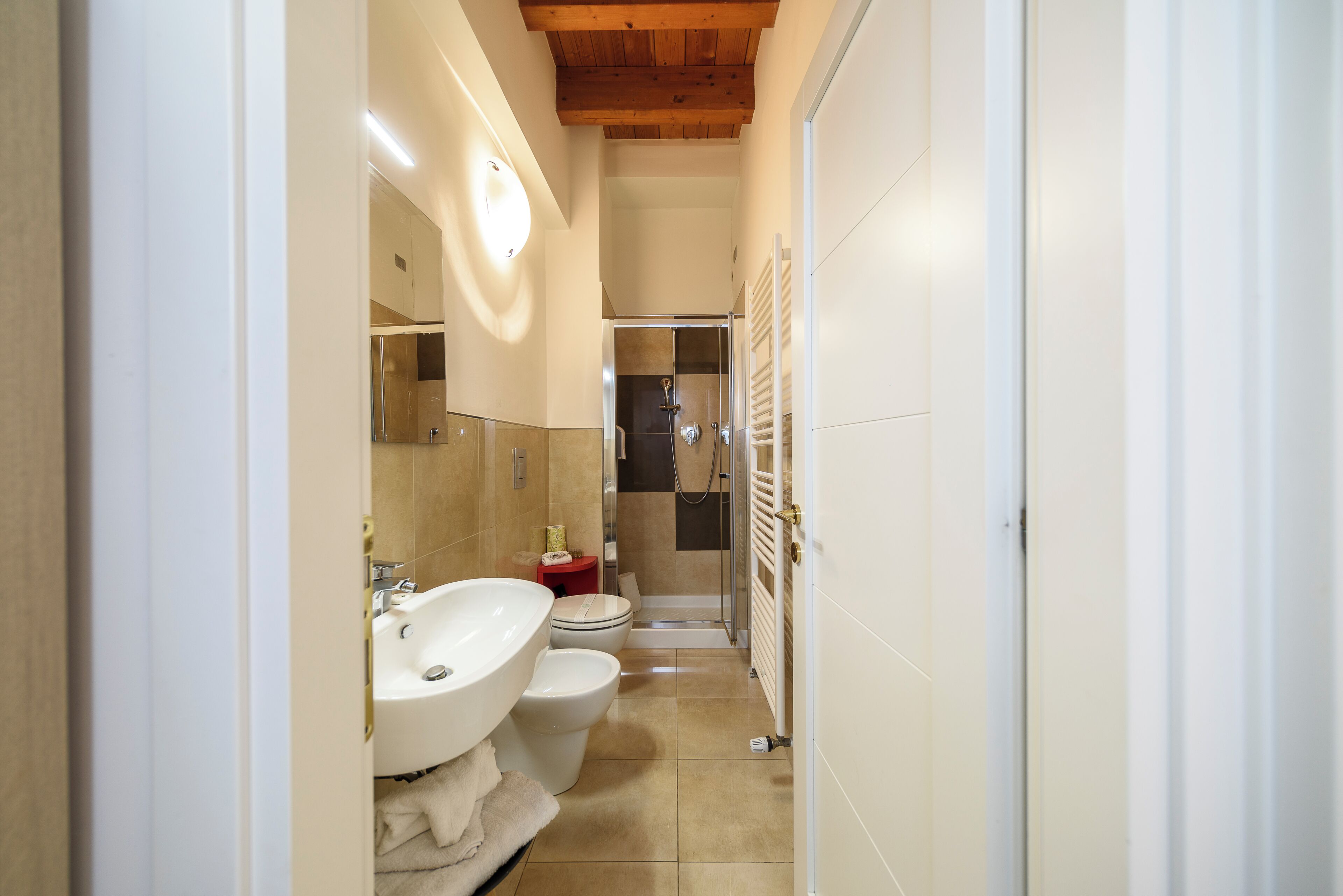 A narrow bathroom with a sink, toilet, and shower area.