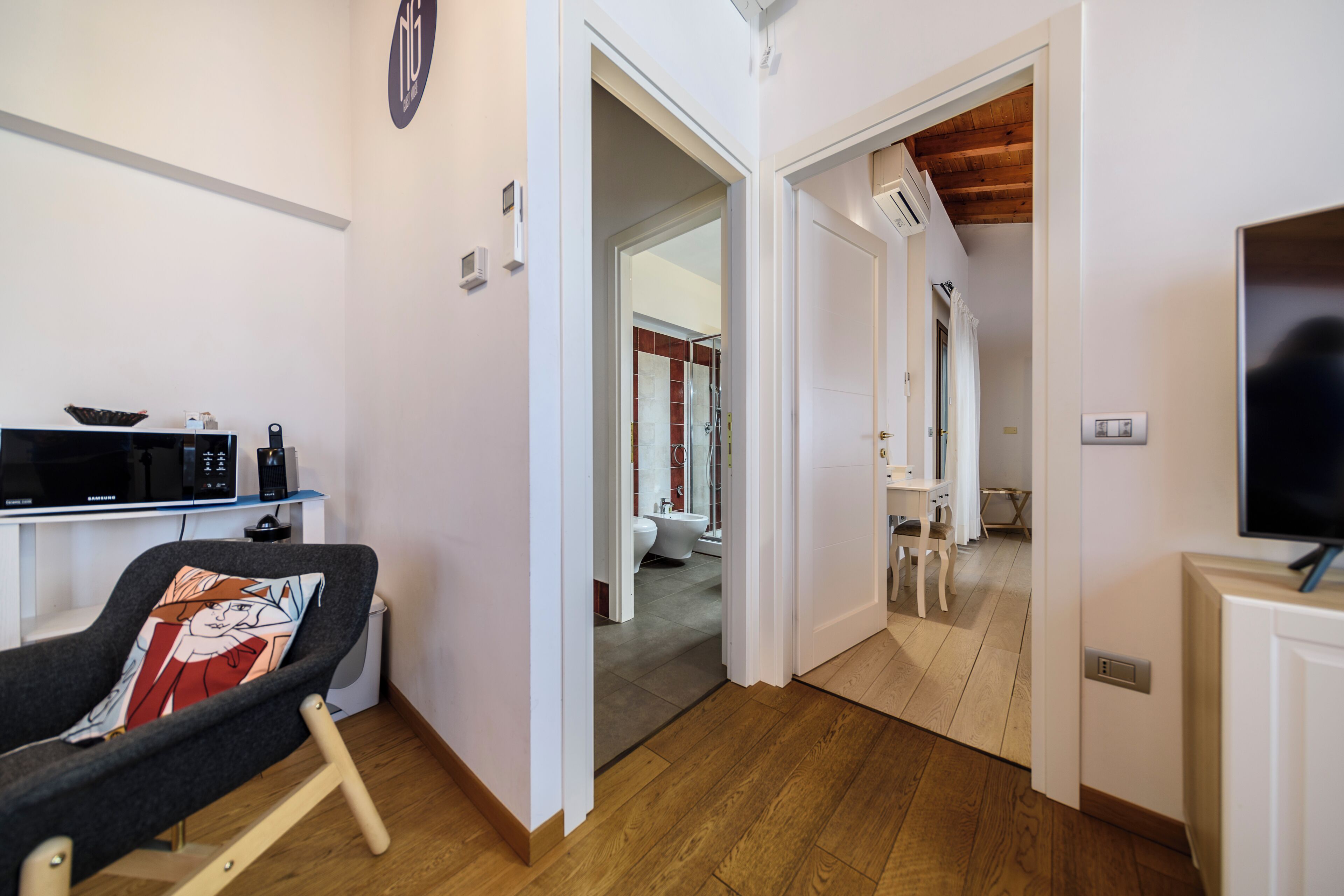 Una habitación moderna con sofá, televisión, microondas y piso de madera.