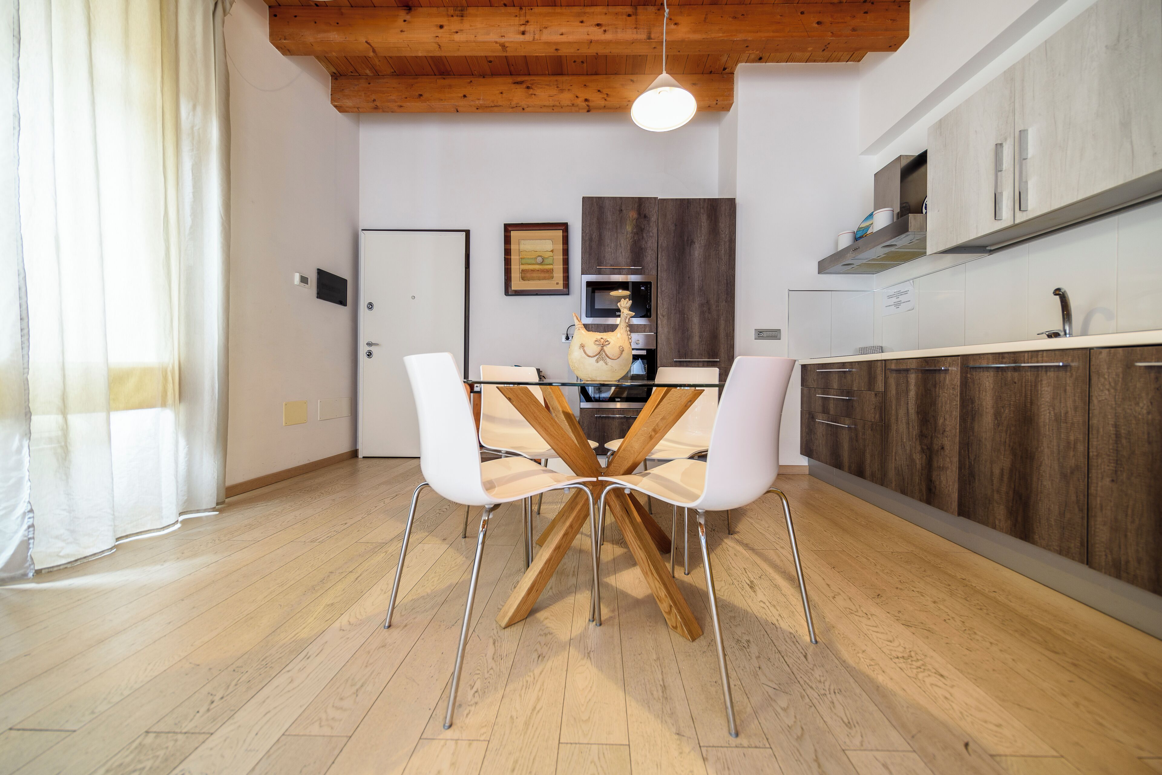 Una cocina moderna con armarios de madera, una mesa de comedor con sillas y una lámpara colgante.