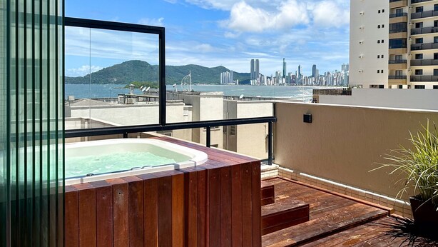 Un balcón con hidromasaje, vistas a un horizonte urbano y una masa de agua.