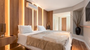 Un dormitorio moderno con una cama grande, paneles de madera, un equipo de aire acondicionado, una mesita de noche y un florero con ramas.