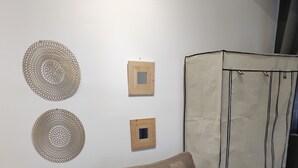 A room with a brown sofa, a green patterned throw, two wall-mounted circular decorations, and a wooden cabinet with a curtain.