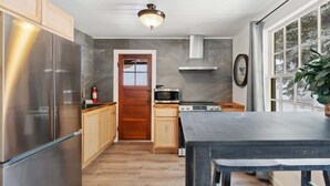 Une cuisine moderne dotée d’appareils électroménagers en acier inoxydable, de meubles en bois et d’une grande fenêtre.