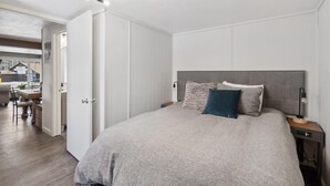 Ein Schlafzimmer mit einem großen Bett, einem Nachttisch, einer Stehlampe und einer Deckenleuchte.