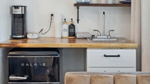 A compact kitchen with a coffee maker, a mini fridge, a sink, and a countertop with storage jars. - Chief's Head Peak (Allenspark)