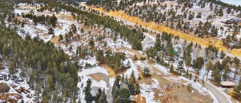 A mountainous landscape with snow-covered terrain, a winding road, and several buildings with thatched roofs.