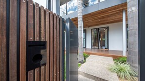 A modern building with a wooden fence, a concrete pillar, and a staircase leading to a wooden deck. - Pet Friendly - Sandringham Sunshine Escape (Sandringham)