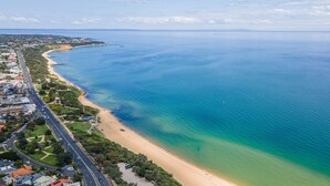 An aerial view of a coastal area with a beach, a road, and residential buildings. - Pet Friendly - Sandringham Sunshine Escape (Sandringham)