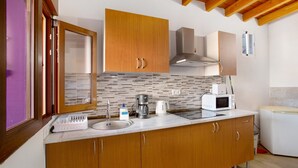 Una cocina con armarios de madera, un lavamanos, una cafetera, un microondas y un tostador.