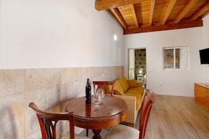 A dining area with a round wooden table, chairs, a bottle, and glasses.