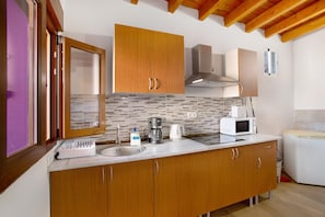Et køkken med træskabe, en vask, kaffemaskine, mikroovn og brødrister.
