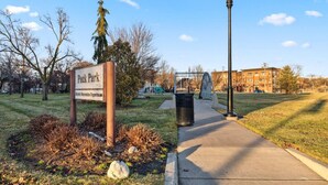 A park entrance with a sign for Peck Park, a pathway, and a lamp post. - Affordable 1-BR by DMC Detroit (Detroit)