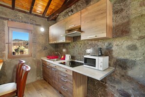 A rustic kitchen with wooden cabinets, a built-in microwave, and a window with a view of the mountains.