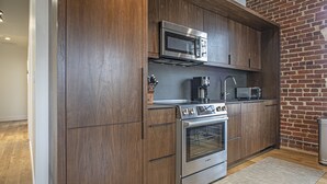 Een moderne keuken met houten kastjes, roestvrijstalen apparatuur en een bakstenen muur.