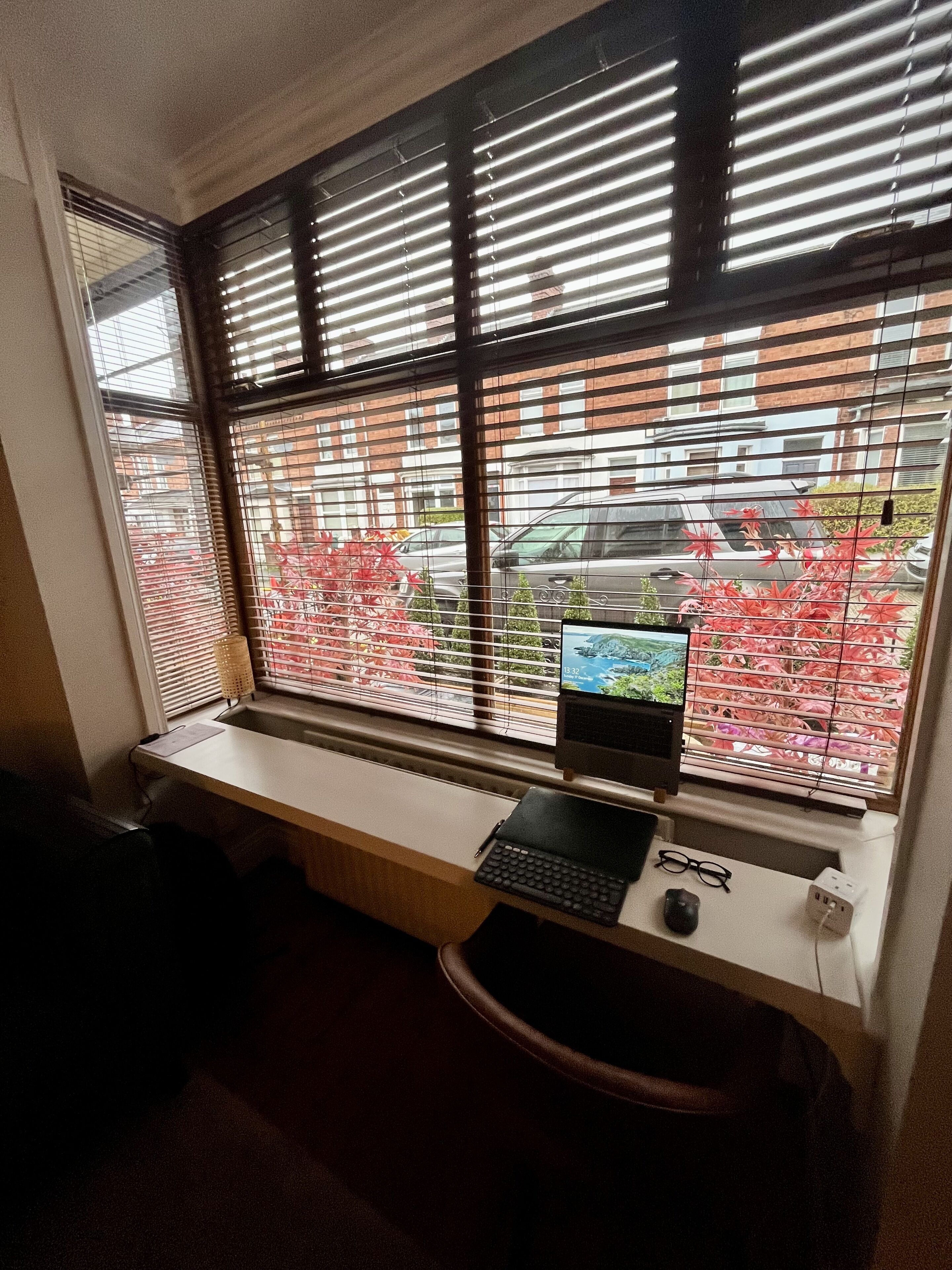 A workspace with a computer, keyboard, and mouse on a desk by a window with blinds.