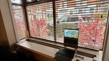 A workspace with a computer, keyboard, and mouse on a desk by a window with blinds.
