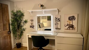 A bedroom with a wooden door, a large mirror with a lighted frame, a black office chair, a bed with white bedding, and a small potted plant. - My Little Place in the City - a modernised 100-year old red brick terrace  (Belfast)