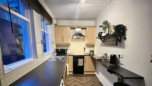 A compact kitchen with a herringbone floor pattern, a central island, and a window on the left. - My Little Place in the City - a modernised 100-year old red brick terrace  (Belfast)