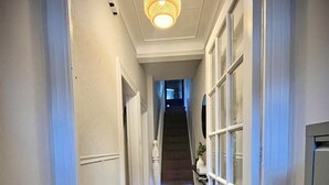 A hallway with a wooden floor, a patterned rug, and a staircase leading to a second floor. - My Little Place in the City - a modernised 100-year old red brick terrace  (Belfast)